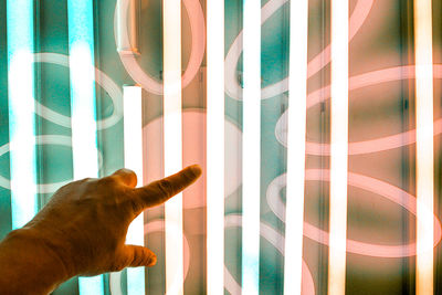 Close-up of hand gesturing towards illuminated glass