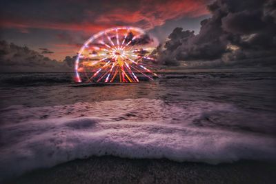 Firework display over sea against sky during sunset