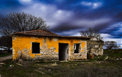 Abandoned house on field against sky