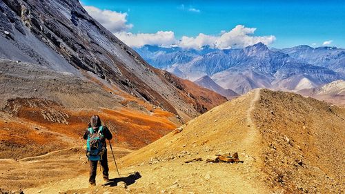 Rear view of man hiking on mountain against sky