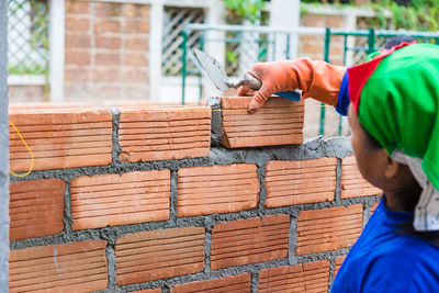 Man working on wood against brick wall