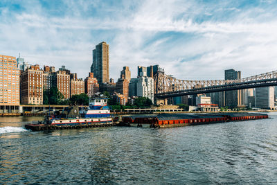 River by modern buildings against sky in city