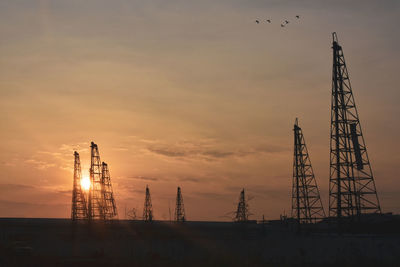 Low angle view of silhouette crane against sky during sunset