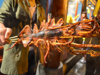 Close-up of hand holding roasted meat at market