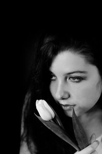 Close-up portrait of a beautiful young woman over black background