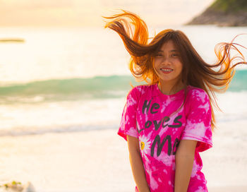 Portrait of happy girl with arms raised on beach