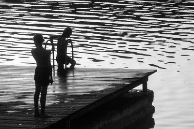 Silhouette of a child in the evening on a pontoon at the edge of a lake