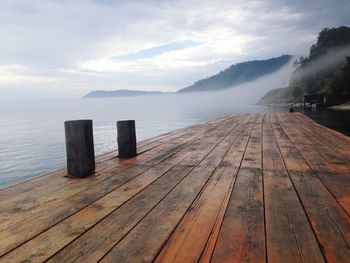 Wooden pier over sea against sky