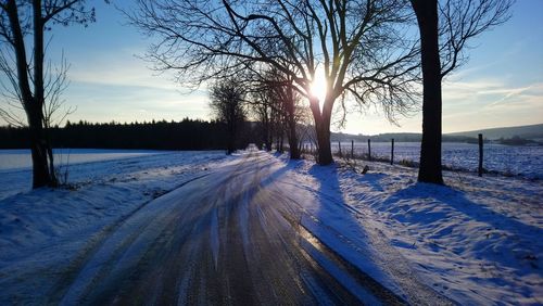 Snow covered field against sky during sunset