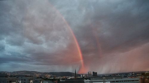 Rainbow over city against sky