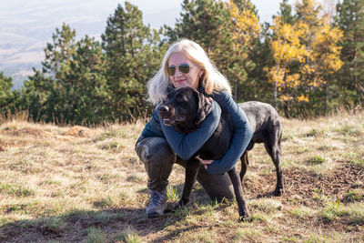 Blond woman and black dog in a mountain landscape on a sunny day