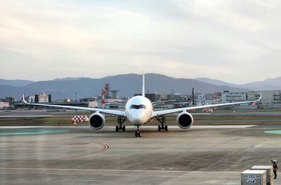 Airplane on airport runway against sky