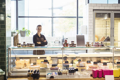 Portrait of confident female owner standing arms crossed at supermarket