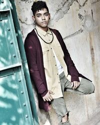 Portrait of young man standing by wall