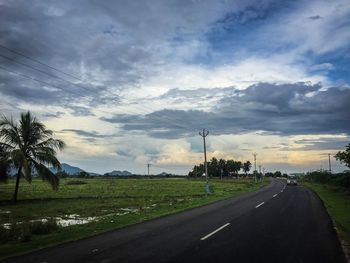 Empty road against cloudy sky at sunset