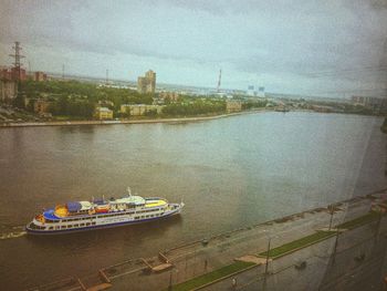 Boat sailing on river against sky in city