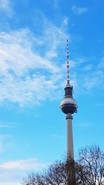 Low angle view of communications tower against cloudy sky