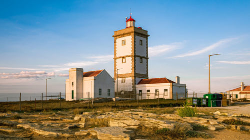 Lighthouse amidst buildings against sky