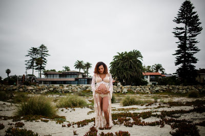 Portrait of woman standing on field against sky