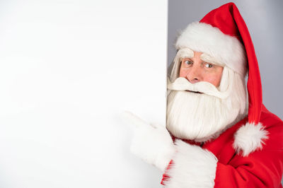 Santa claus peeks out from behind an ad on a white background. merry christmas