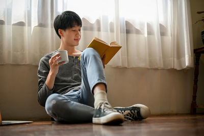 Young woman using laptop while sitting on bed at home