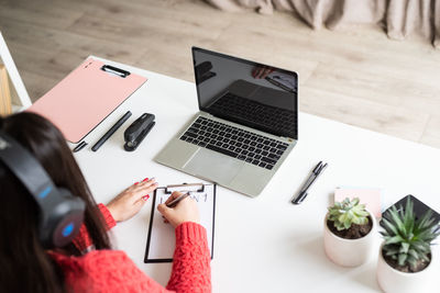 High angle view of businesswoman writing on clipboard