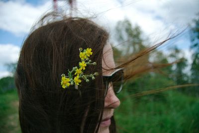 Close-up of girl on plant at field against sky