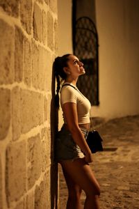 Young woman standing against wall