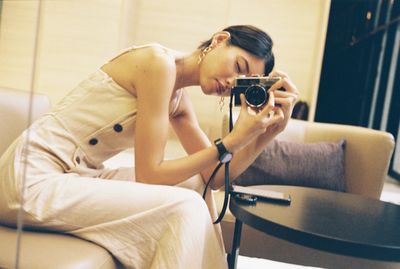 Young woman using mobile phone while sitting on sofa at home