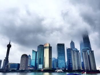 Skyscrapers in city against cloudy sky