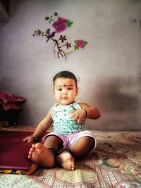 Cute baby girl sitting on bed at home