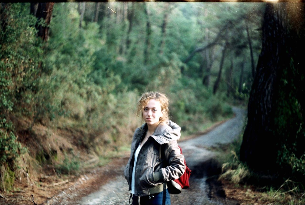 tree, forest, portrait, looking at camera, plant, one person, land, focus on foreground, casual clothing, nature, day, standing, front view, women, leisure activity, clothing, woodland, childhood, hair, outdoors, hairstyle, scarf