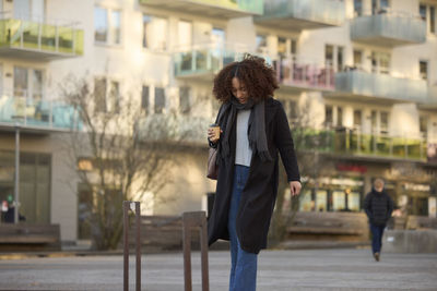 Beautiful woman with takeaway coffee walking on street