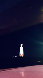 Illuminated street light against sky at night