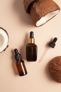 Bottles of coconut oil and fresh coconuts on beige background. coconut natural cosmetics.