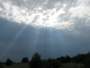 Low angle view of sunlight streaming through clouds