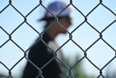 Close-up of chainlink fence with man standing in background