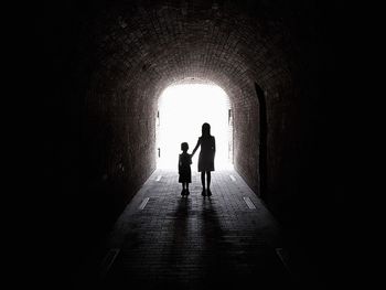 Rear view of silhouette people walking in tunnel