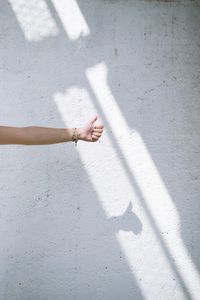 Cropped hand showing thumbs up against wall