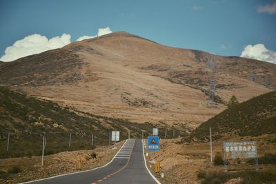 Road leading towards mountains against sky