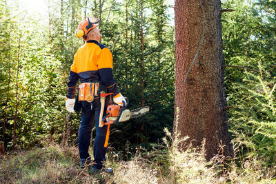 Rear view of man standing by plants in forest