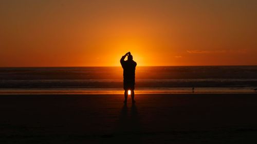 Silhouette standing on beach during sunset