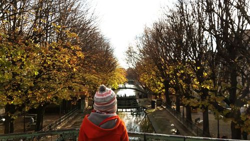 Rear view of woman with umbrella against trees