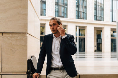 Full length of man using phone while standing outdoors