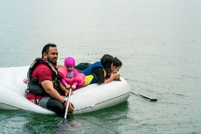 Family wearing life jackets paddling on an inflatable boat in a lake