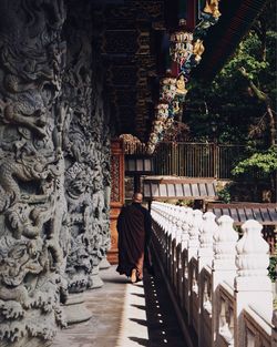 Rear view of monk wearing traditional clothing walking by temple