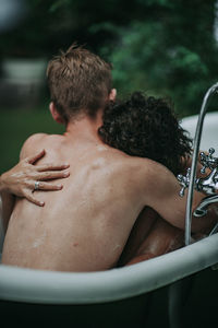 Rear view of shirtless man and woman in bathroom