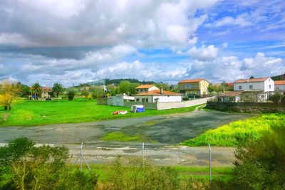 Houses on field by buildings against sky