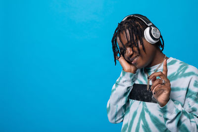 Portrait of young woman wearing sunglasses against blue background