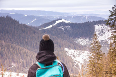 Rear view of friends standing on snow covered mountain